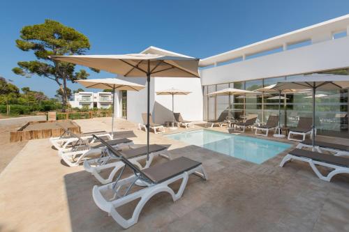 a pool with lounge chairs and umbrellas next to a building at Radisson Blu Resort Al Hoceima in Al Hoceïma
