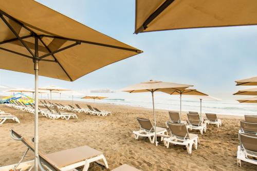 a group of chairs and umbrellas on a beach at Radisson Blu Resort Al Hoceima in Al Hoceïma