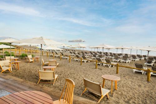 a beach with chairs and tables and umbrellas at Radisson Blu Resort Al Hoceima in Al Hoceïma