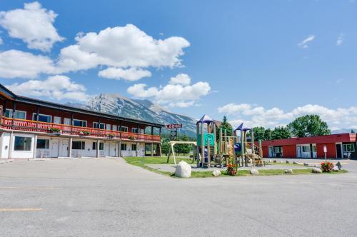 an empty parking lot in front of a building with a playground at Rocky Mountain Ski Lodge in Canmore