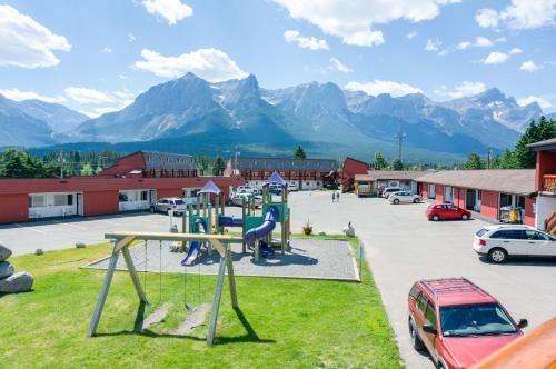 a playground in a parking lot with mountains in the background at Rocky Mountain Ski Lodge in Canmore
