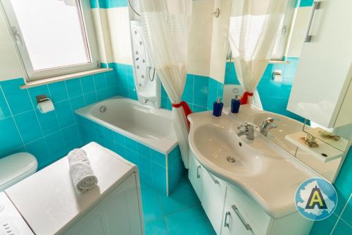 ein blau-weißes Badezimmer mit einem Waschbecken und einer Badewanne in der Unterkunft Mariquita - Appartamento fronte mare a Silvi in Silvi Marina