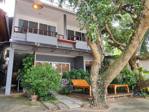 a building with a tree and a bench in front of it at Bliss Resort Krabi in Klong Muang Beach