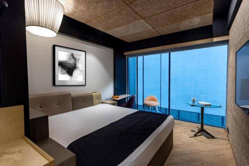a bedroom with a bed and a large window at NUO By juSTa in New Delhi