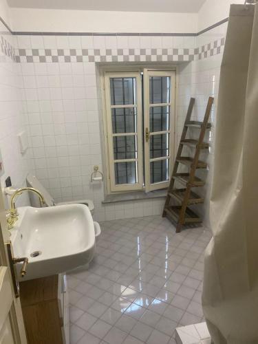 a white bathroom with a sink and a ladder at Corte Storica in Cortemaggiore