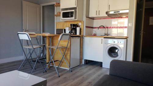 une petite cuisine avec un lave-linge, une table et des chaises dans l'établissement Studio spacieux proche plage. Wi-fi, climatisation, à Bormes-les-Mimosas