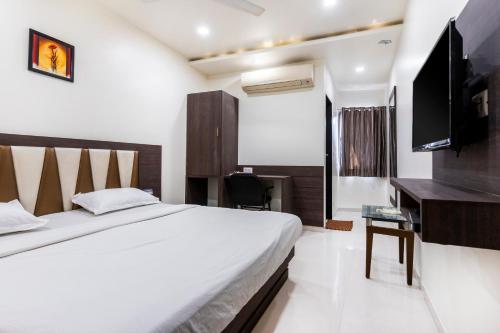 a bedroom with a bed and a desk and a television at Hotel Ashish in Ahmedabad