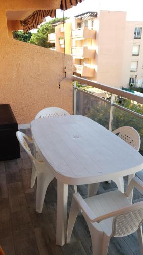 une table blanche et des chaises sur un balcon dans l'établissement Studio spacieux proche plage. Wi-fi, climatisation, à Bormes-les-Mimosas