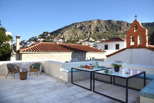 a patio with a table and chairs on a roof at Cactus Hydra - Art Apartments in Hydra