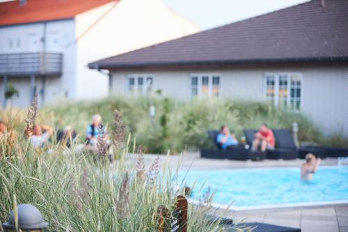 een groep mensen die rond een zwembad zitten bij Color Hotel Skagen in Skagen