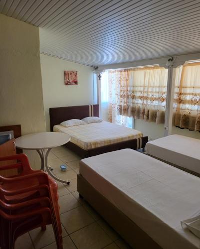 a room with two beds and a table and a chair at Athanasiadis Studios in Nea Vrasna