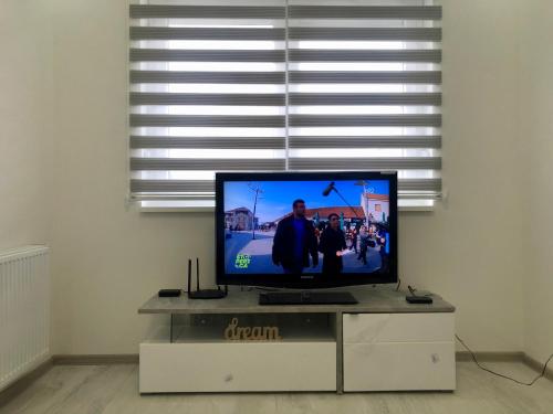 a flat screen tv sitting on a stand in front of a window at Apartman Silver Star in Sombor