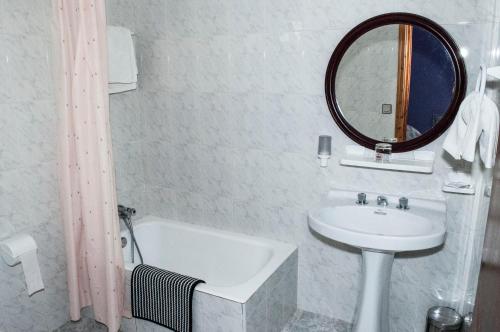 a bathroom with a sink and a mirror and a tub at Hotel Alto de las Estazadas in Canales