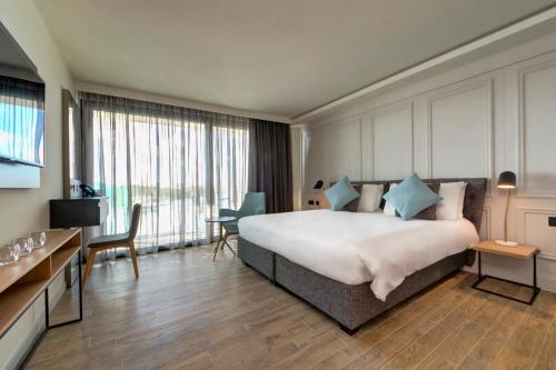 ein Hotelzimmer mit einem großen Bett und einem Schreibtisch in der Unterkunft Land's End, Boutique Hotel in Sliema