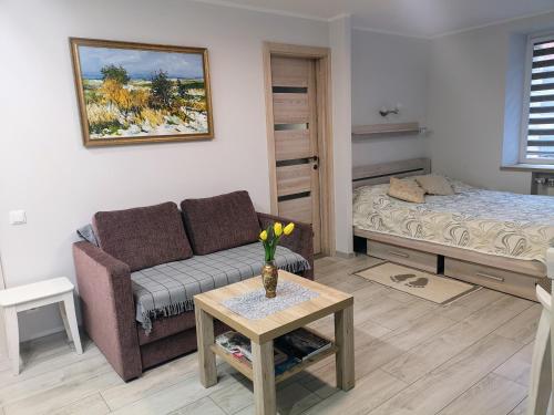 uma sala de estar com um sofá e uma cama em Miško studija em Nida