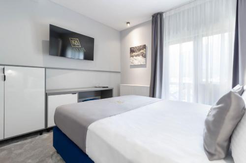 a hotel room with a white bed and a window at Kayus in Buşteni