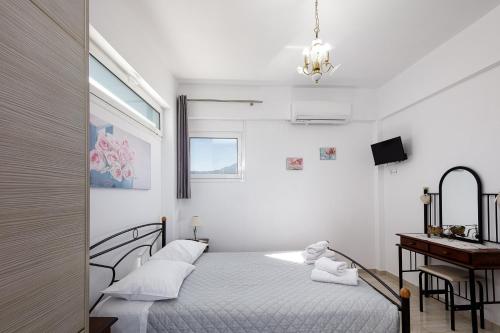 biała sypialnia z łóżkiem i biurkiem w obiekcie Vourvahis Seaview Apartments w mieście Karotí