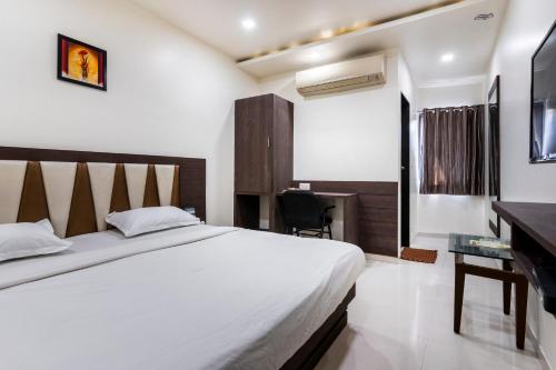 a bedroom with a large bed and a desk at Hotel Ashish in Ahmedabad