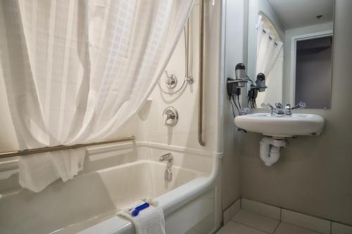 a white bathroom with a sink and a bath tub at Microtel Inn & Suites Sault Ste. Marie in Sault Ste. Marie