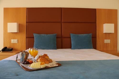 a tray of food and drinks on a bed at Hotel Atlantida Sol in Figueira da Foz