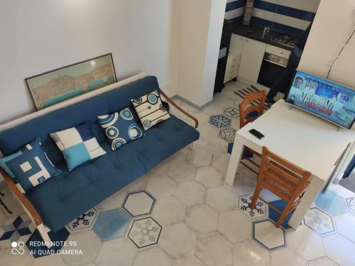 sala de estar con sofá azul y mesa en casetta, en Isquia