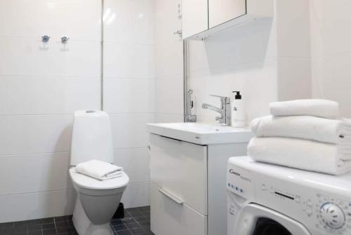 y baño blanco con lavabo y lavadora. en Stylish new 1br apt in Aurinkolahti, en Helsinki