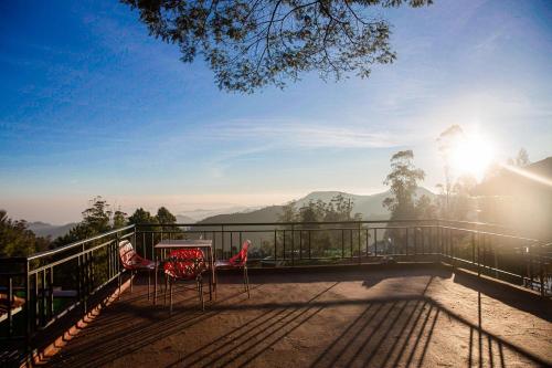 a balcony with two chairs and a table and the sun at Vista Suites Doddabetta Ooty By Bestinn Leisure in Ooty