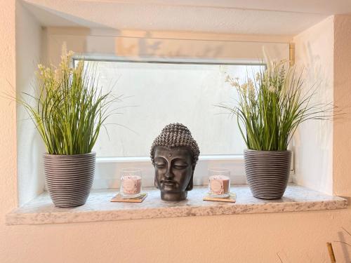 a statue sitting on a window sill with two plants at Am Wildbach bei Passau in Saming