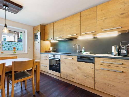 a kitchen with wooden cabinets and a table and a sink at House in H ttau near Salzburg Airport in Hüttau