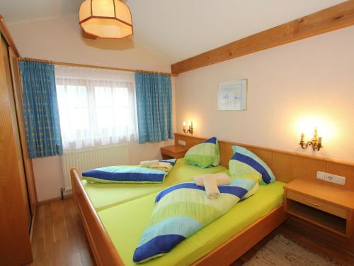 een slaapkamer met 2 bedden met blauwe en groene kussens bij Quaint Apartment in L ngenfeld with Sauna in Huben