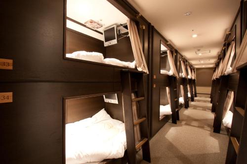 a row of bunk beds in a room at HEARTS Capsule Hotel & Spa Nakasu -Male only- in Fukuoka