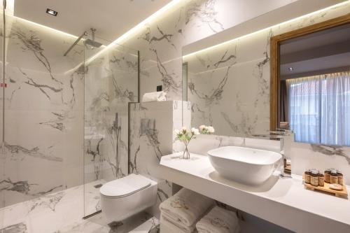 W łazience znajduje się umywalka, toaleta i lustro. w obiekcie Emily's Luxury Suites w mieście Pefkochori