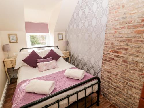 a bed in a room with a brick wall at Bridge End Bothy in Wooler