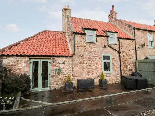 an old stone house with a red roof at Bridge End Bothy in Wooler