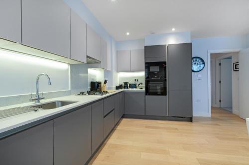 uma grande cozinha com armários brancos e um lavatório em Belmore 1 & 2 Bedroom Luxury Apartments with Parking in Stanmore, North West By 360 Stays London em Stanmore