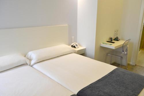 a room with two beds and a telephone in it at Hotel Alda San Bieito in Santiago de Compostela
