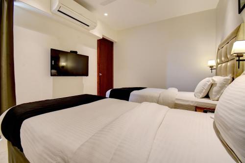 a hotel room with two beds and a tv at Elite Homes in Aurangabad