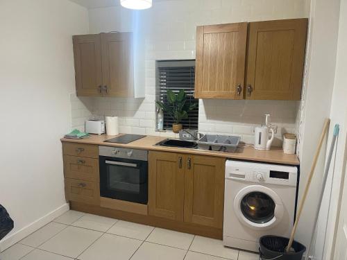 uma cozinha com um lavatório e uma máquina de lavar roupa em 2 Bed Flat Right in Centre of Portrush town em Portrush