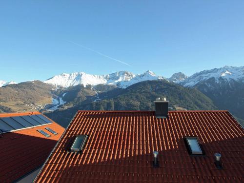 a red roof with snow covered mountains in the background at Chalet in Fiss near Ski Lifts in Fiss