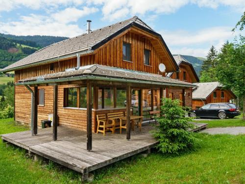 a log cabin with a wooden deck and a table at Chalet in Sankt Georgen near ski area in Sankt Georgen ob Murau
