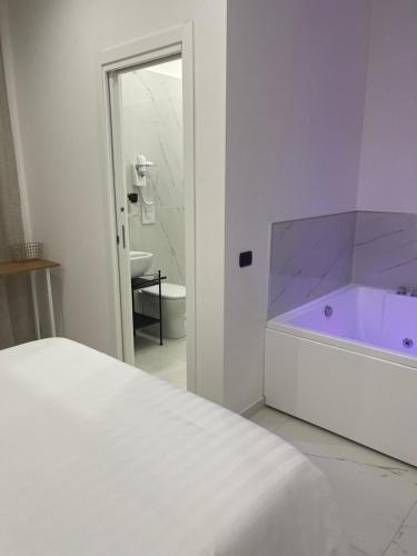 a white bedroom with a purple tub in a bathroom at Costantino Home in Pompei