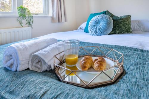 a tray of croissants and orange juice on a bed at Pierocks Wickets Luxury Entire house, Free Parking and WI-FI in Maidenhead in Maidenhead