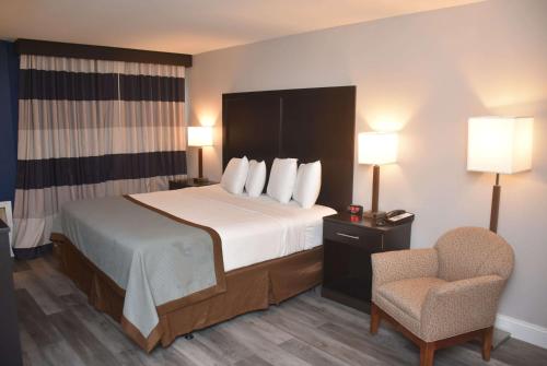 a hotel room with a bed and a chair at Ramada by Wyndham Vineland Millville Area in Vineland