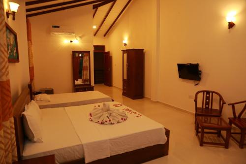 a hotel room with two beds and a television at Villa A.SMS in Induruwa