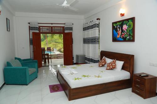 a bedroom with a bed and a blue chair at Villa A.SMS in Induruwa
