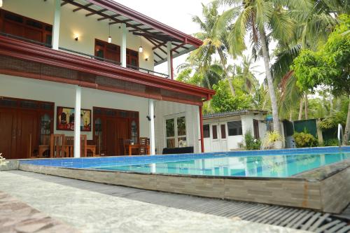 a swimming pool in front of a house at Villa A.SMS in Induruwa