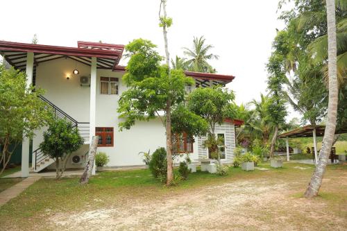 a white house with trees in front of it at Villa A.SMS in Induruwa