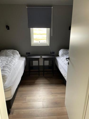 2 camas en una habitación con mesa y ventana en Dalamynni, en Hólmavík