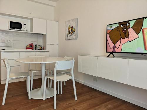 uma cozinha com uma mesa e uma televisão na parede em Family Suite Appartments Orchidea Blu em Rimini