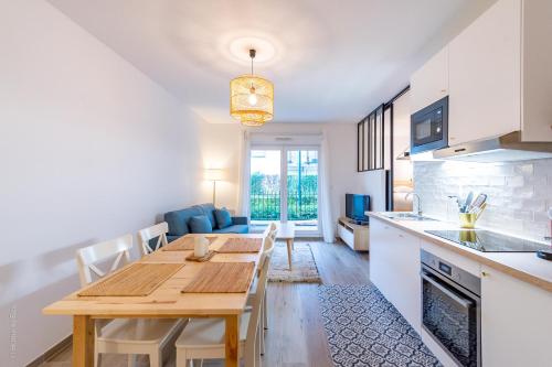 een keuken en eetkamer met een houten tafel en stoelen bij Woody Cocon by Plaza - Proche Disneyland Paris in Montévrain